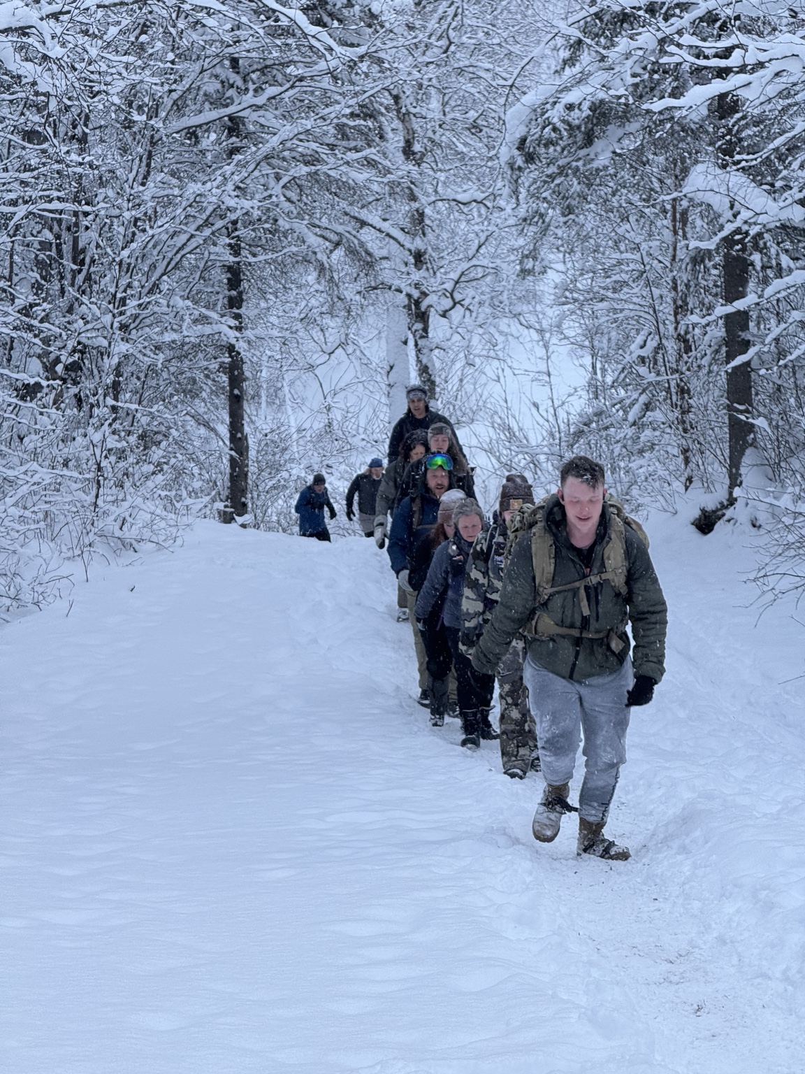 Participants moving single-file up a snow-covered trail during a Toughest Alive winter event.