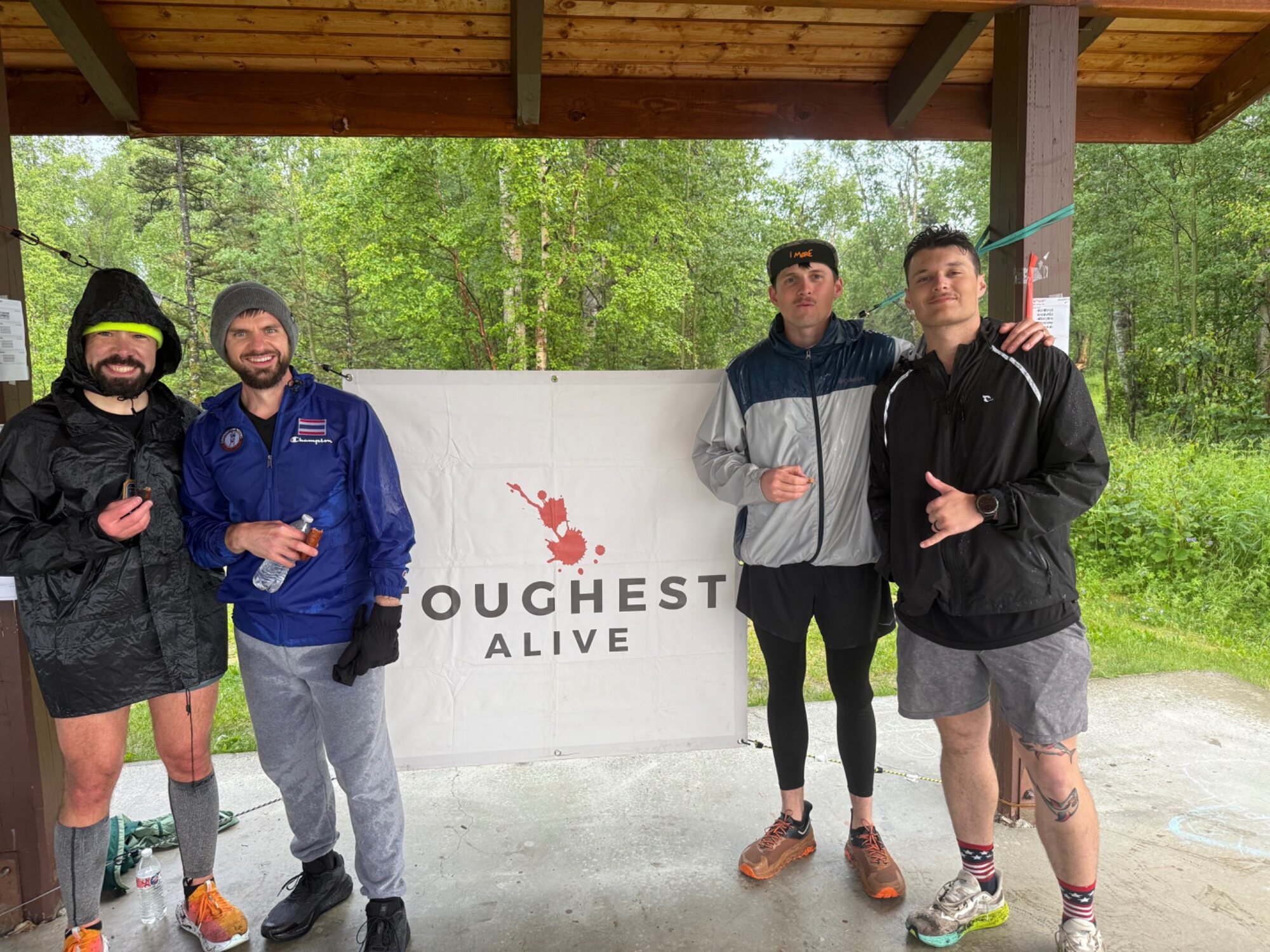 Participants gathered beside the Toughest Alive banner in the rain.