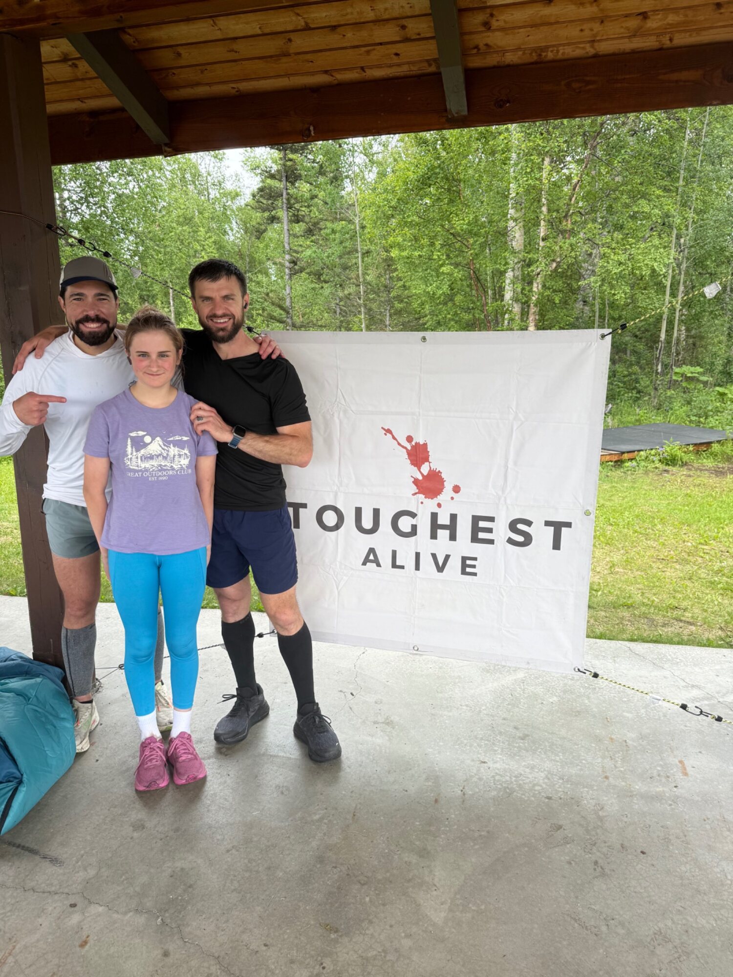Dossie standing with Michael Ortiz and Andrew Vigorito beside a Toughest Alive banner.