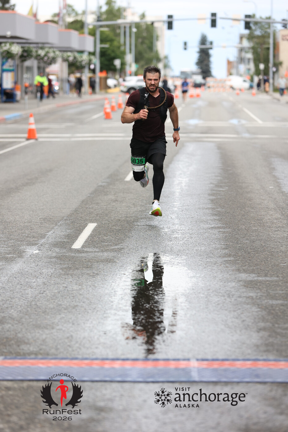 Andrew running toward a race finish line on a wet city street.
