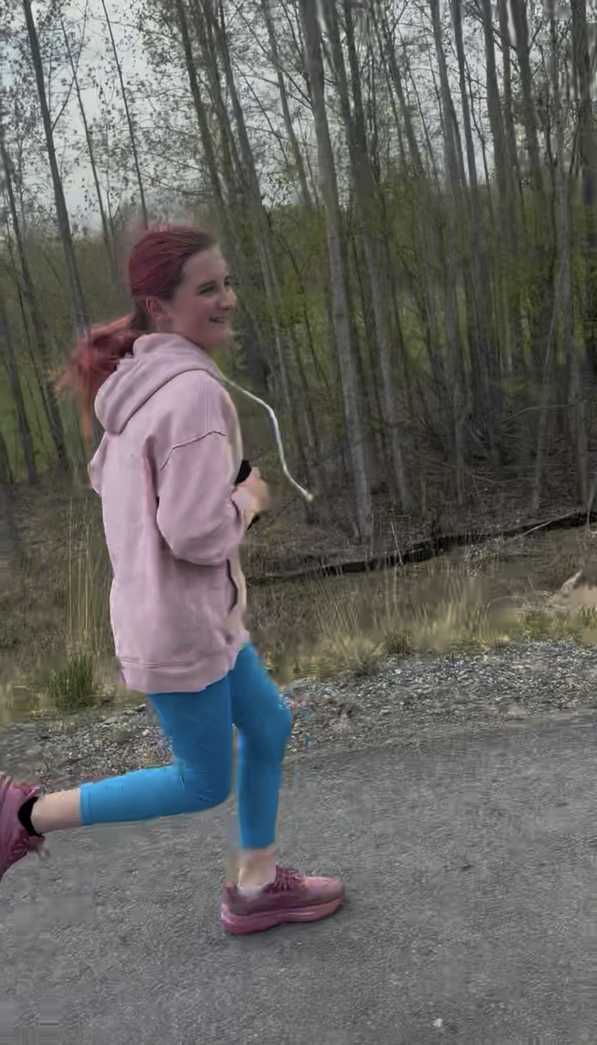 Hadassah smiling while running on a wooded road during her 100-mile effort.