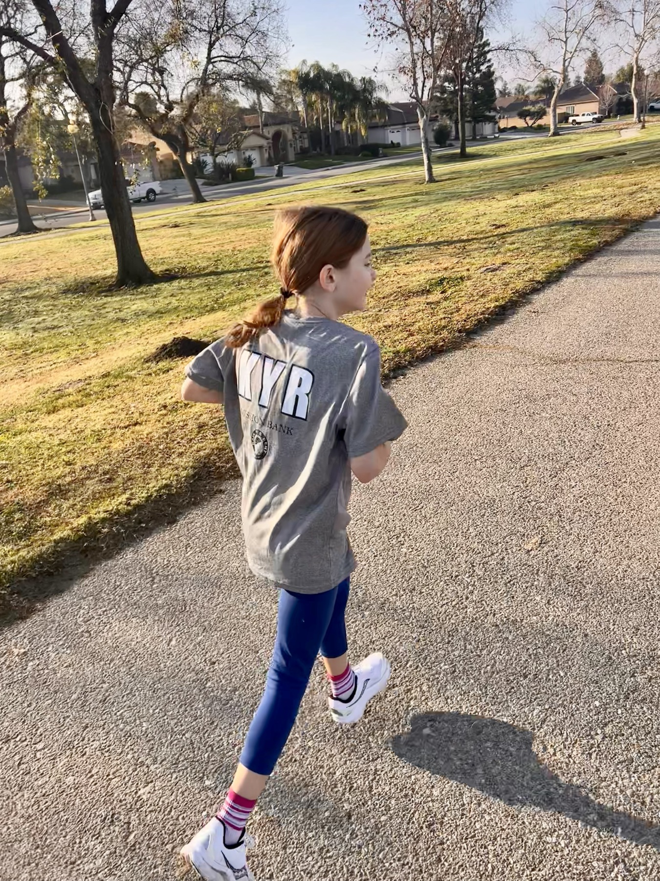 Sophia moving along a sunlit neighborhood path.