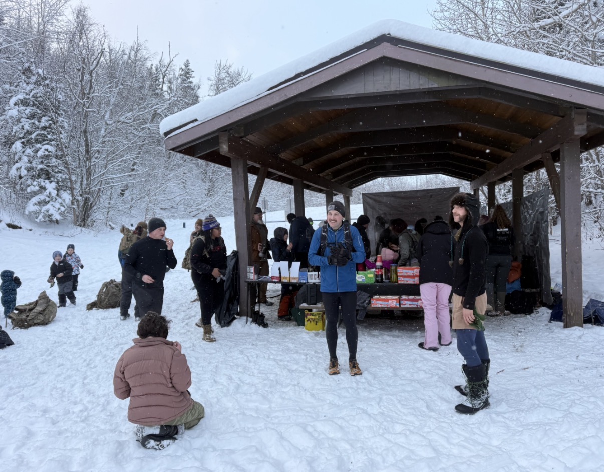 People gathering under a shelter during a snowy outdoor event.